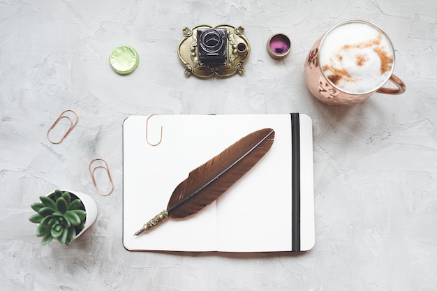 Biurko biurowe niezależnego pisarza z kawy, notatnik, pióro, atrament, soczysta roślina na szaro