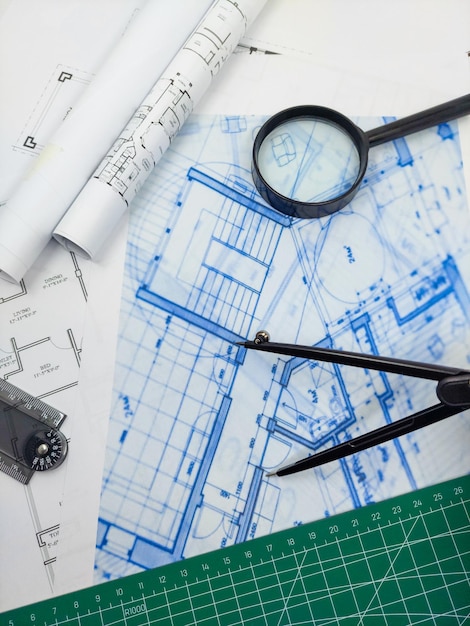 Zdjęcie biurko inżyniera architekta plany planów i model domu z kompasem linijki i lupą