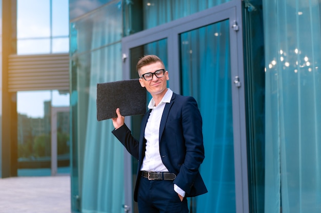 Biznes. Biznesmen okulary z folderem stojący budynek biurowy wejście przystojny kaukaski mężczyzna biznes osoba portret miasto korporacyjny budynek tło udany młody dorosły kierownik