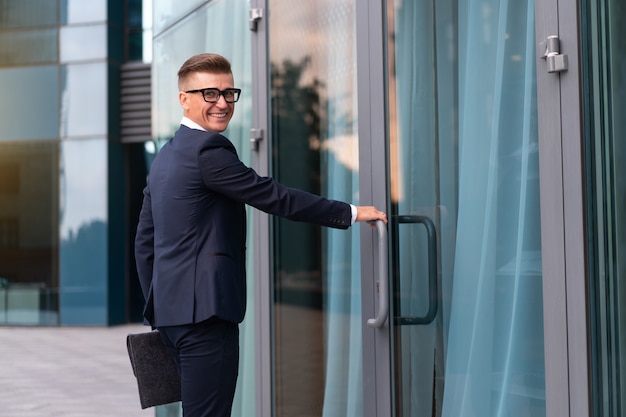 Biznes. Biznesmen okulary z folderem stojący budynek biurowy wejście przystojny kaukaski mężczyzna biznes osoba portret miasto korporacyjny budynek tło udany młody dorosły kierownik