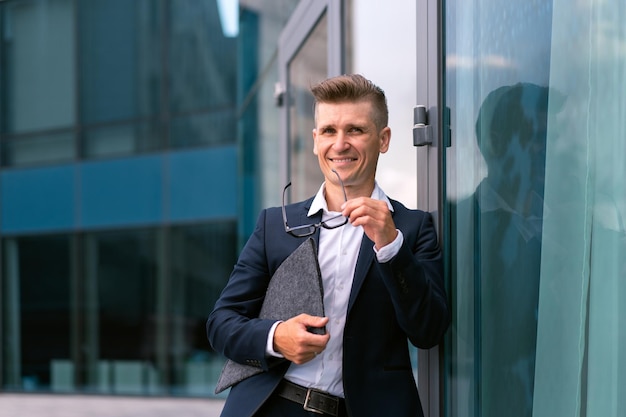 Biznes biznesmen okulary z folderem stojący budynek biurowy wejście przystojny kaukaski mężczyzna biznes osoba portret miasto korporacyjny budynek tło udany młody dorosły kierownik