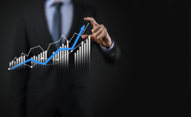 Biznes człowiek posiadający holograficzne wykresy i statystyki giełdowe zyskuje. Koncepcja planowania rozwoju i strategii biznesowej. Wyświetlacz dobrej ekonomii na ekranie cyfrowym.