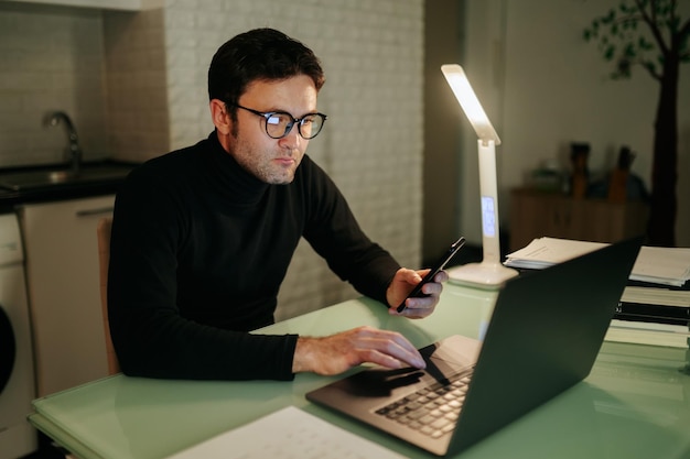 Biznes e-commerce w nocy zdjęcie w pomieszczeniu mężczyzny pracującego do późna na laptopie z okularami na rękach