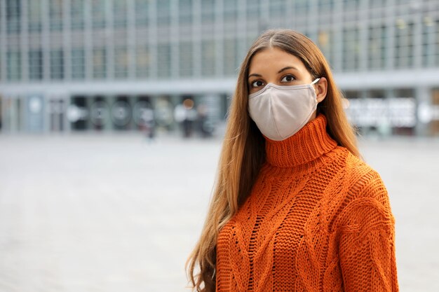 Biznes kobieta nosi maskę ochronną stojąc na ulicy