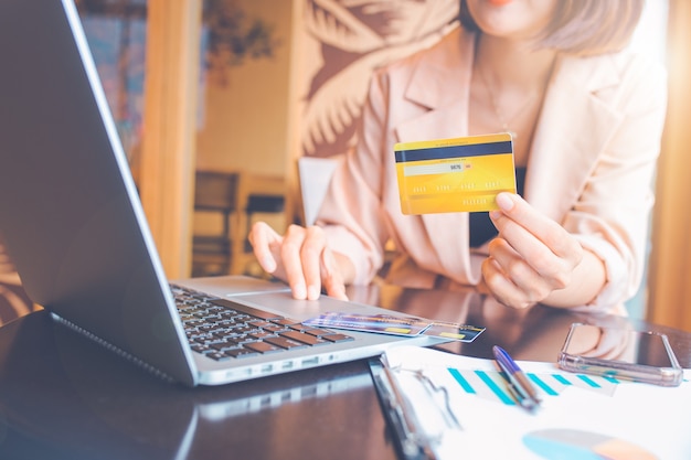 Biznes kobieta posiadania karty kredytowej i zakupy online przy użyciu laptopa.