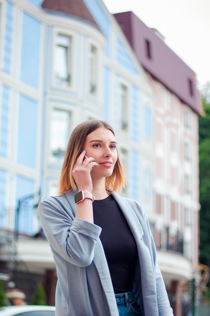 Biznes kobieta rozmawia przez telefon na zewnątrz. Portret pięknej uśmiechniętej dziewczyny w modnym off