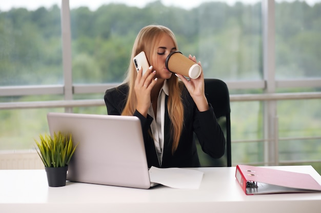 Biznes kobieta rozmawia przez telefon picia kawy.