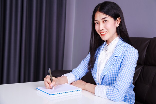biznes kobieta siedzi przy biurku i pisze notatkę na notebooku