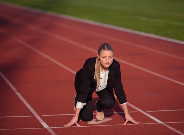 biznes kobieta w pozycji startowej gotowa do biegu i sprintu na torze lekkoatletycznym