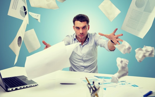biznes, ludzie, stres, emocje i koncepcja niepowodzenia - zły biznesmen rzucający papiery w biurze na niebieskim tle
