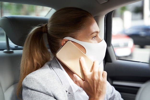 Biznes podczas koronawirusa biznesowa kobieta nosząca ochronną maskę na twarz rozmawiająca przez telefon komórkowy