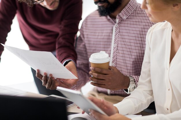 Zdjęcie biznes, startup i koncepcja ludzi - międzynarodowy zespół kreatywny z papierami, tabletem i filiżanką kawy w biurze