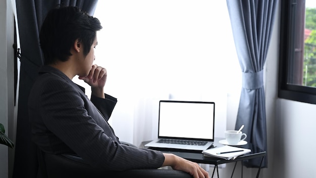 Biznesmen analizujący dane biznesowe na laptopie w nowoczesnym biurze