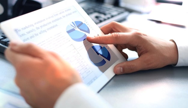 Biznesmen analizujący statystyki finansowe wyświetlane na ekranie tabletu