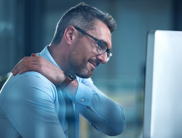 Biznesmen ból szyi i stres w stawach z powodu wypalenia artretyzmu i siedzenia przy komputerze w nocy Dojrzały mężczyzna twórca stron internetowych i technik w biurze dla globalnego projektu firmy i nadgodziny