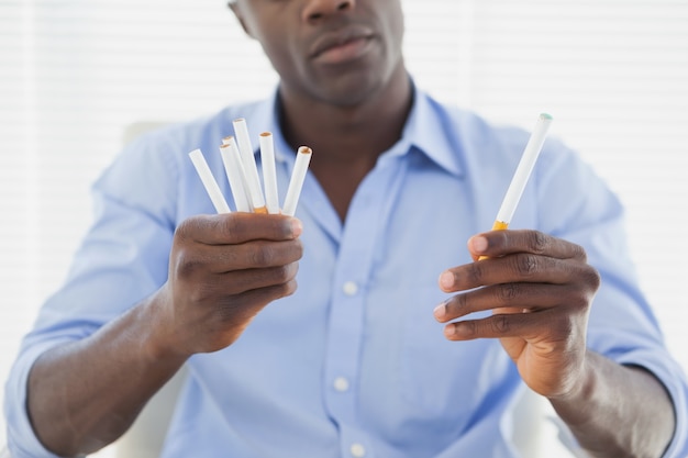 Biznesmen decydujący między elektronicznymi lub normalnymi papierosami