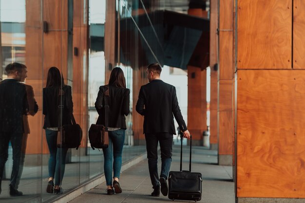 Biznesmen i bizneswoman rozmawiając i trzymając bagaż podróżujący w podróży służbowej, niosąc w rękach świeżą kawę. Pomysł na biznes. Zdjęcie wysokiej jakości