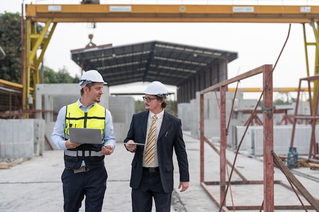 Biznesmen i inżynier idą i rozmawiają o projekcie na placu budowy