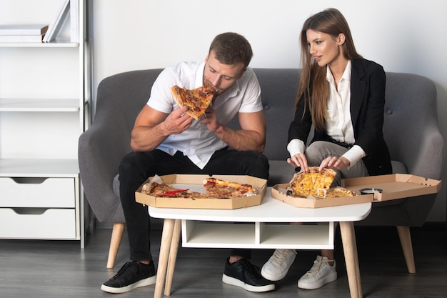 Biznesmen i kobieta biznesu mają przerwę na lunch w biurze jedząc kawałek pizzy szczęśliwi ludzie