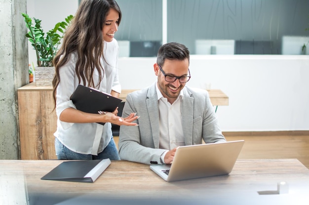 Biznesmen i kobieta omawiają dane finansowe na laptopie w biurze
