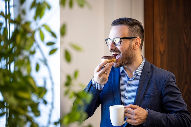 Biznesmen je pączki i pije kawę w pracy