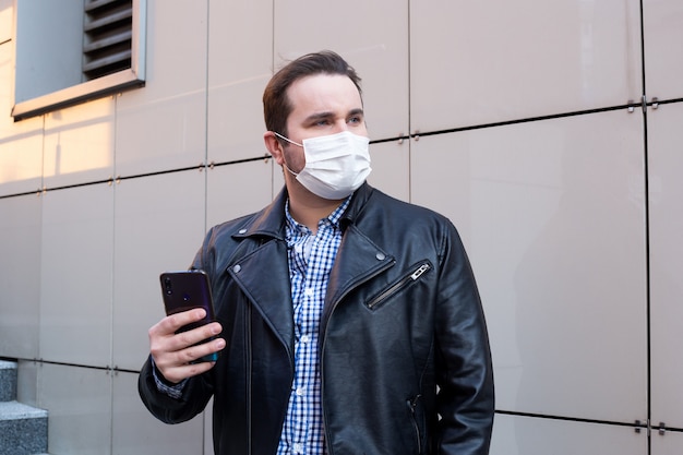 Biznesmen jest ubranym maskę ochronną używać smartphone