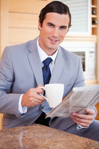 Biznesmen ma kawę i czytelniczą wiadomość w kuchni
