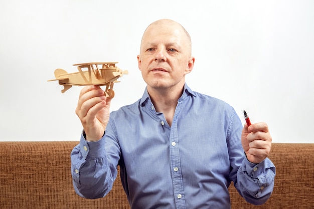 Biznesmen marzy o swoim osiągnięciu Biznesowy pomysł na marzenie Mężczyzna trzyma w rękach drewniany model samolotu