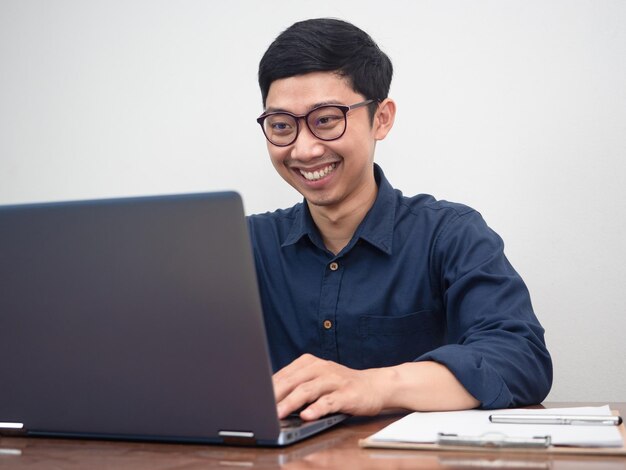 Biznesmen nosi okulary zadowolony z pracy przy użyciu laptopa przy stole w miejscu pracy