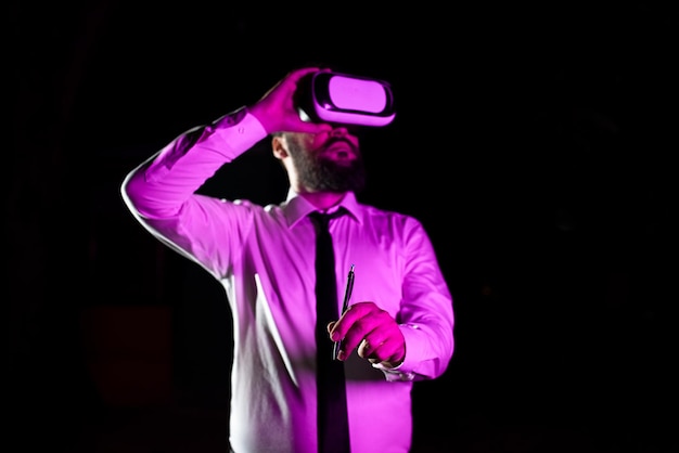 Biznesmen noszący zestaw słuchawkowy trzymający długopis podczas szkolenia zawodowego poprzez noszenie symulatora wirtualnej rzeczywistości Światło padające na mężczyznę prezentującego futurystyczną technologię
