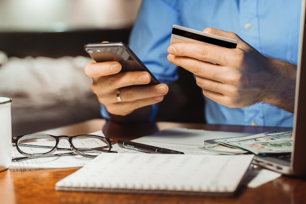 Zdjęcie biznesmen oblicza miesięczne wydatki, podatki, sprawdza płatności kartami kredytowymi, dochody, płaci rachunki online.