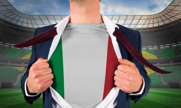 Biznesmen otwierający koszulę, aby odsłonić flagę włoch na dużym stadionie piłkarskim z brazylijskimi fanami