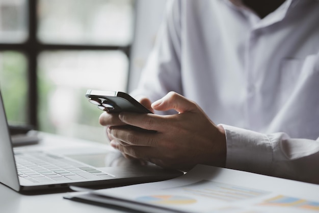 Biznesmen patrzący na informacje finansowe z telefonu komórkowego sprawdza dokumenty finansowe firmy jest dyrektorem firmy rozpoczynającej działalność Koncepcja zarządzania finansami