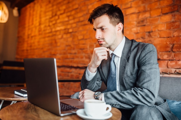 Biznesmen patrzeje jego laptop w caffe