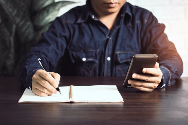 biznesmen pisania na notebooku i patrząc na telefon