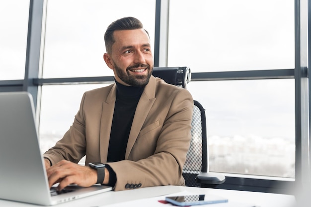 Biznesmen piszący na laptopie w biurze i odwracający wzrok