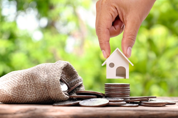 Biznesmen posiadający modelowy dom na stosie monet koncepcji inwestycyjnej Oprocentowanie kredytu hipotecznego i budowy domu