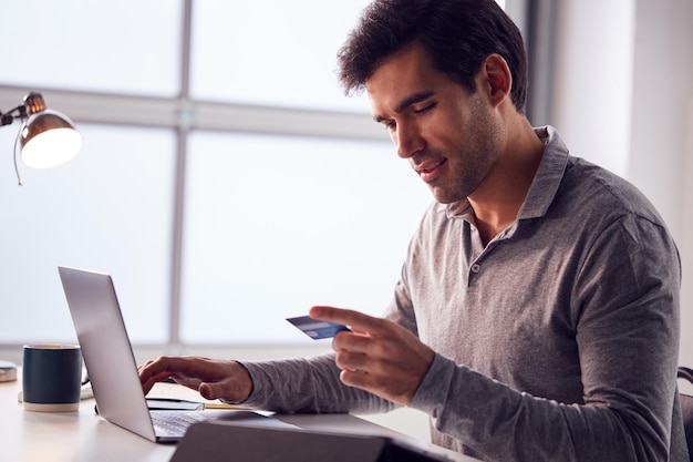 Biznesmen Pracujący Do Późna Na Laptopie Przy Biurku W Biurze Dokonywanie Płatności Online Kartą Kredytową