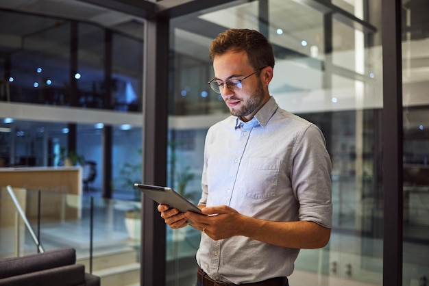 Biznesmen pracujący na tablecie w nocy dla marketingu cyfrowego raport online w biurze Menedżer lub pracownik czytający komunikację w Internecie na temat propozycji technologii podczas pracy do późna w pracy startowej