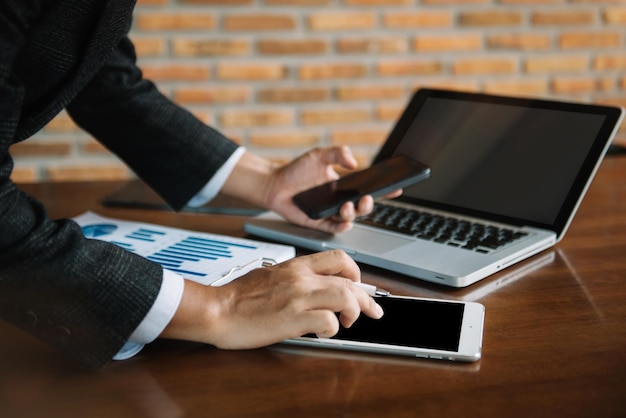 Biznesmen pracujący w biurze z laptopem typu tablet i smartfon oraz papierami na biurku