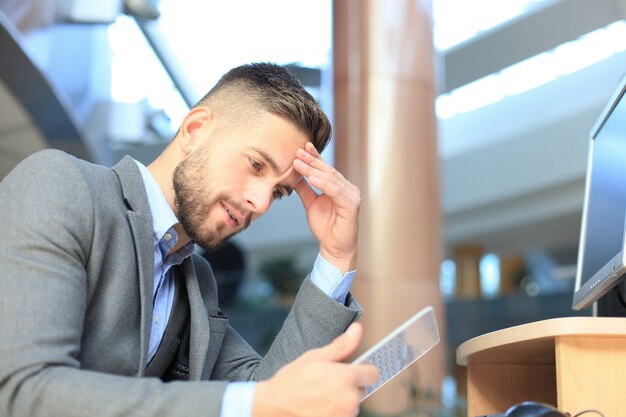 Biznesmen pracujący w biurze z przezroczystym tabletem i komputerem pc.