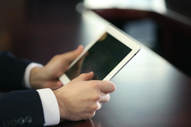 Biznesmen pracujący z tabletem przy drewnianym stole zbliżenie