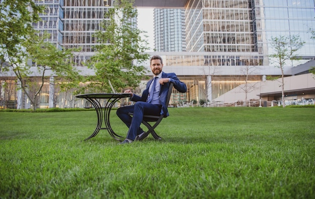 Biznesmen pracujący zdalnie w nowoczesnym parku Portret biznesmena siedzącego na zewnątrz w miejscu pracy na tarasie w nowoczesnym centrum biznesowym