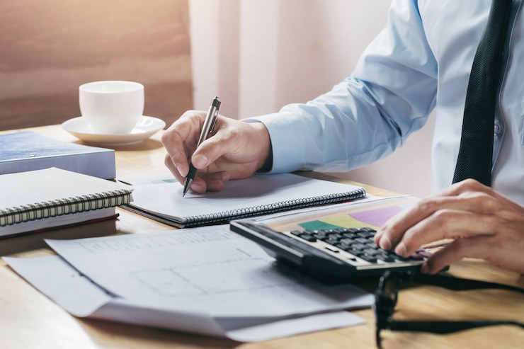 Zdjęcie biznesmen pracy accountand finanse z wykorzystaniem kalkulatora i pióra na stole w biurze