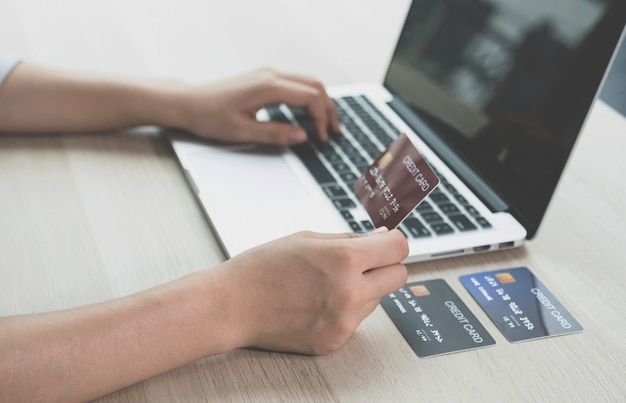 Zdjęcie biznesmen ręka trzyma kartę kredytową na zakupy online na komputerze przenośnym z domu, płatności e-commerce, bankowość internetową, wydawanie pieniędzy na następne wakacje.