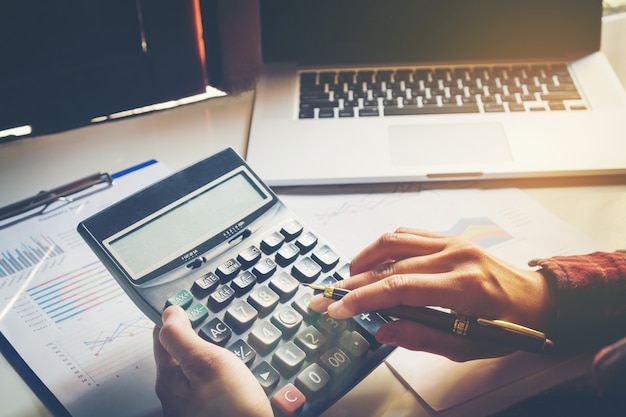 Biznesmen ręki z kalkulatorem i używać laptop przy biurem i dane finansowe