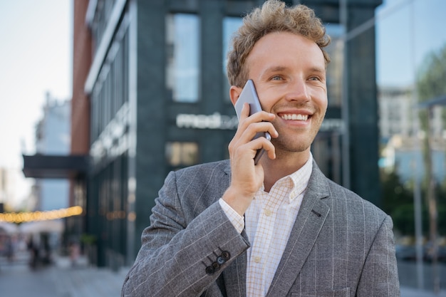 Biznesmen rozmawia przez telefon komórkowy, słuchając dobrych wieści na ulicy Udany biznes