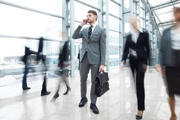 Biznesmen rozmawia przez telefon stojący w tłumie chodzących ludzi