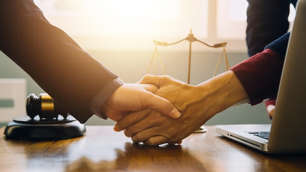 Biznesmen ściska dłoń, aby przypieczętować umowę z prawnikami lub prawnikami partnerskimi omawiającymi umowę kontraktową
