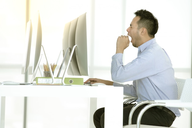 biznesmen siedzi i ziewa w nowoczesnym biurze